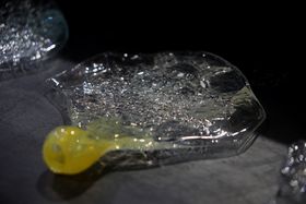 Partially yellow and bulbous, partially clear, flat and textures glass object