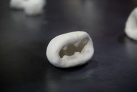 A small, white ceramic object resembling a cave opening or a mouth