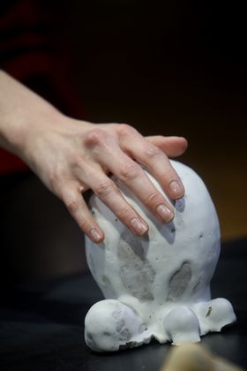 Hand touching a white, round ceramic object
