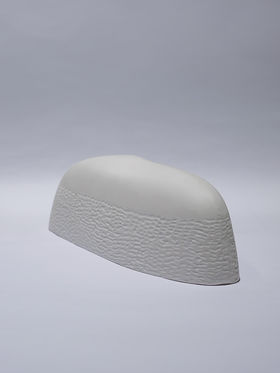 A curved white shape with indentations covered with a white layer that masks the indentations of the shape