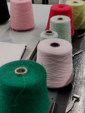 A collection of green, pale pink, white, sage, red, olive green and pink industrial sized threads