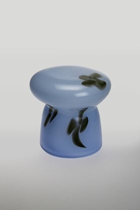 A blue sculptural object with three black flowers