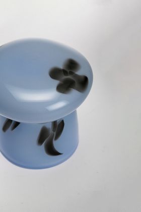 A blue sculptural glass object with black flowers