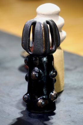 A darkly glazed ceramic sculpture with a metal shine