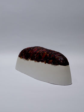 A curved white shape covered in a layer of red algae