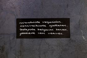 Handwritten text in Finnish on a black paper