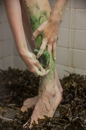 Somebody washing their feet with a green foamy soap, algae in the background