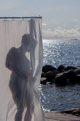 A person being a shower curtain on the beach