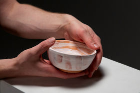 Two hands embracing a ceramic bowl