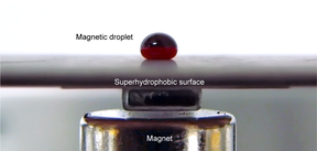 A ferrofluid droplet sitting on a measurement surface in the oscillating droplet tribometer measurement scheme. The magnet underneath the surface is also seen.