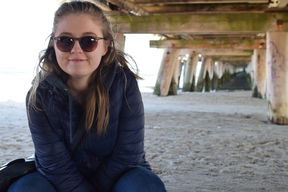 Aalto University / A girl sitting on sand with sunglasses on / Laura McLeod
