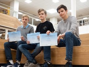 Henrik Aalto, Roope Salmi and Unto Karila sitting on the stairs and showing their certificates