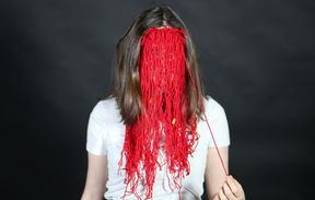 A person behind red mask made of yarn.