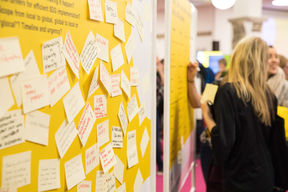 A yellow workshop wall with lots of sticky notes with text