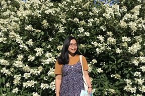 Linh standing in front of a flower wall smiling