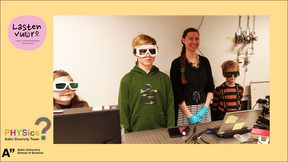 Three children with goggles standing with a young researcher at a computer