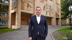 A man in a suit standing in front of the Aalto Töölö building.