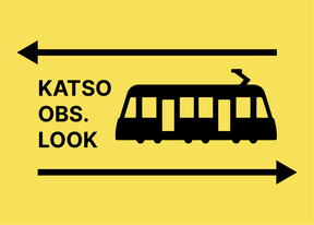 A yellow sign with the words Katso, Obs, Look, a tram icon next to them, with an arrow above pointing to left and an arrow below pointing to right. All text and icons are in black. This is part of a campaign to increase safety near the new light rail tram.