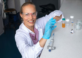 Professor Jaana Vapaavuori wearing a lab coat and safety glasses.