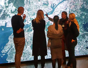 Four students in front of a wall-sized image of a city map.