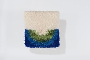 A square textile art piece in white, green and two different shades of blue
