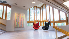 Two armchairs and an acrylic painting by Hans-Christian Berg decorates a stairs landing in Dipoli, Aalto University
