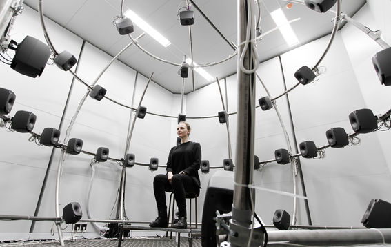 A person sitting at aalto acoustics lab's multichannel anechoic chamber photo benoit alary