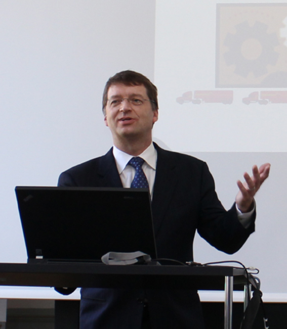 Tuomas Sandholm giving a speech behind a laptop and wearing a suit