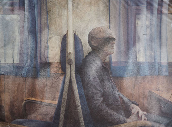 Night train by the artist. A two dimensional drawing of a passenger sat on a train, reclining in a seat with ghostly faces appearing around him