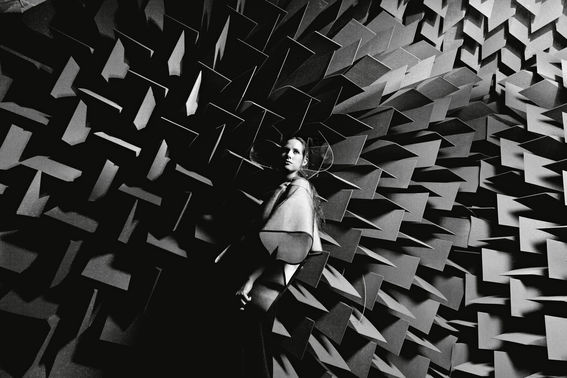 Black and white image on student wearing futuristic clothes in front of the architectural geometric structure.