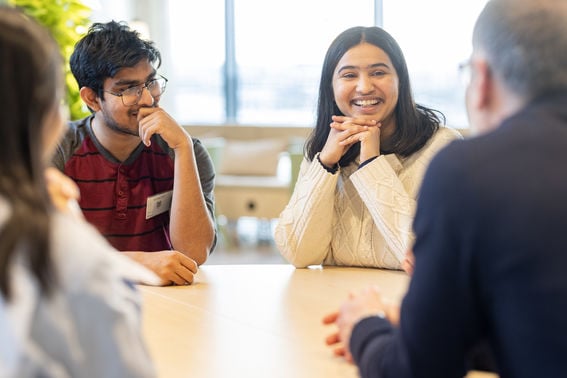 Students sitting around a table and smiling