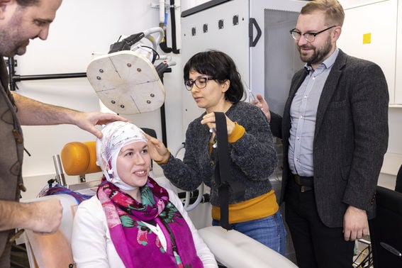 To succeed, this project will pull together skills and expertise from many fields. Pantelis Lioumis (from left), Matilda Makkonen, Ana Maria Soto and Tuomas Mutanen demonstrating the use of the new TMS device. Photo: Mikko Raskinen.