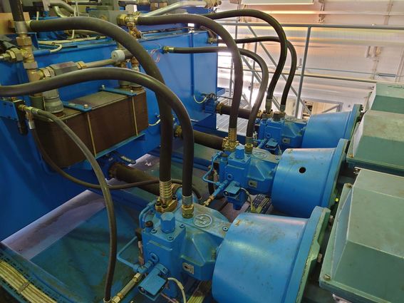 Three identical hydraulic pumps in a row connected to a large tank. 