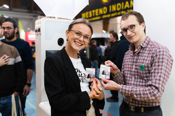 two people smiling and holding photographs in their hands