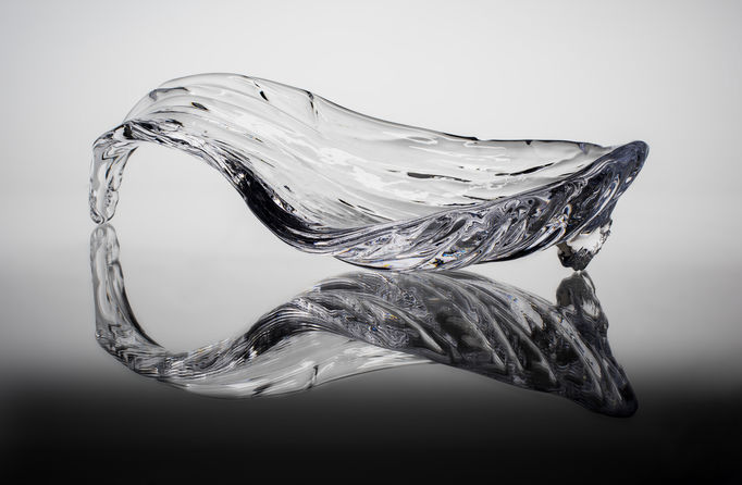 an organic-shaped glass piece with a reflection underneath