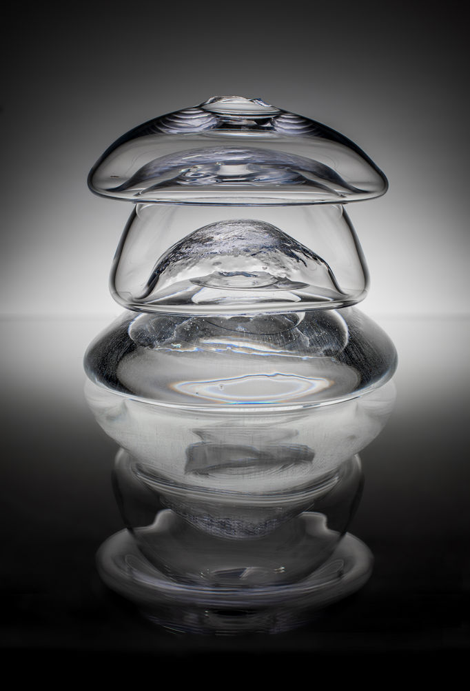 a multi-layered clear glass piece with a reflection underneath