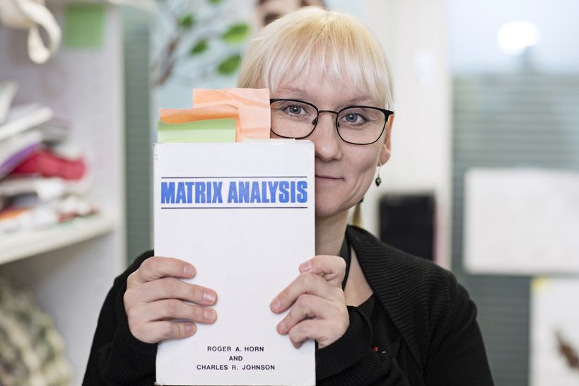 Professor Imonen holding a copy of a textbook up to the camera