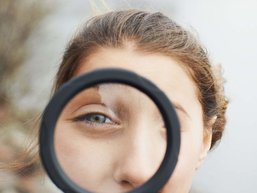 Girl looking through a magnifying glass