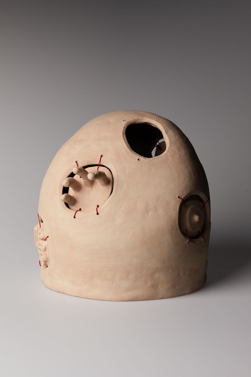 a ceramic sculpture of which body parts reach out of