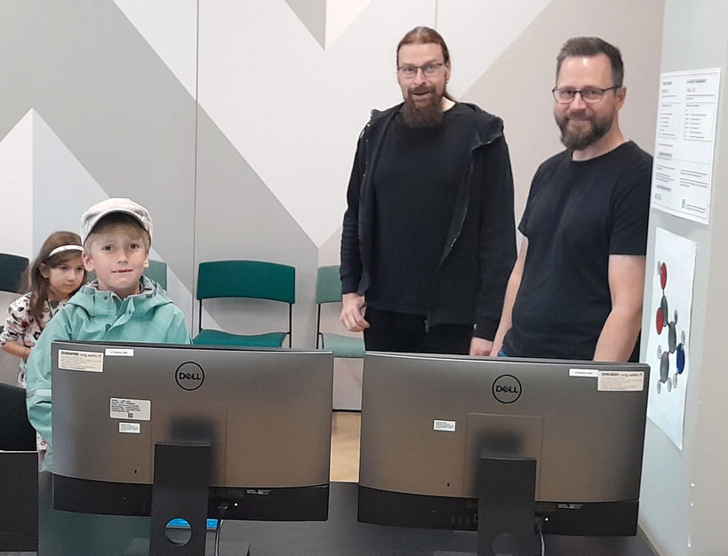 Photo showing 2 children with 2 CEST researchers at monitors