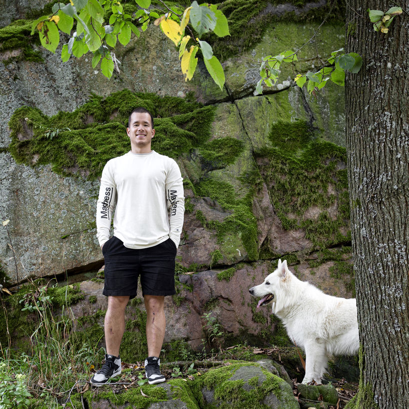 Mies seisoo kiven edessä vierellään valkoinen suuri koira