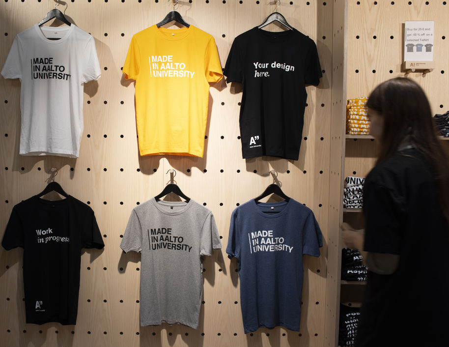 Colorful Made in Aalto University -t-shirts hanging at Aalto University Shop's wall