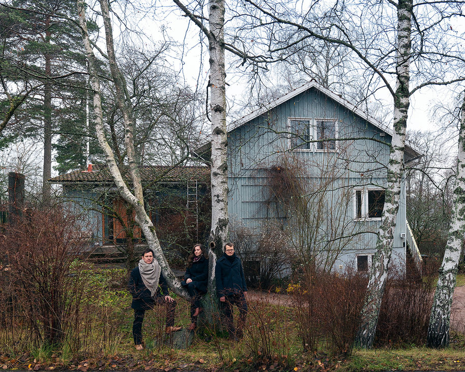 Kuraattorit Laura Berger, Philip Tidwell ja Kristo Vesikansa seisovat Helsingin Jollaksessa sijaitsevan Puutalo Oy:n rakennuksen edustalla.