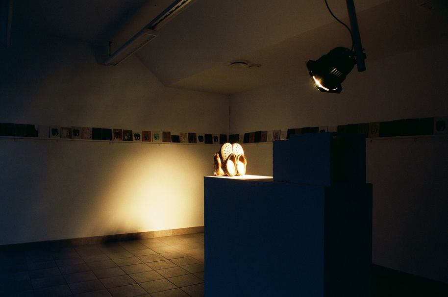 exhibition space with ceramic tiles on the wall and working shoes in the middle in a spotlight