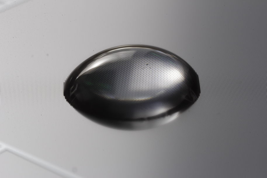 Photo of a water droplet on a grey hydrophobic surface.