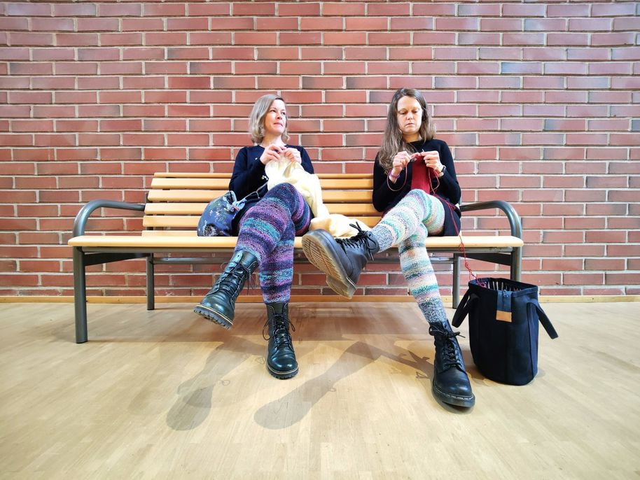 Kaksi naista istuu penkillä neulomassa