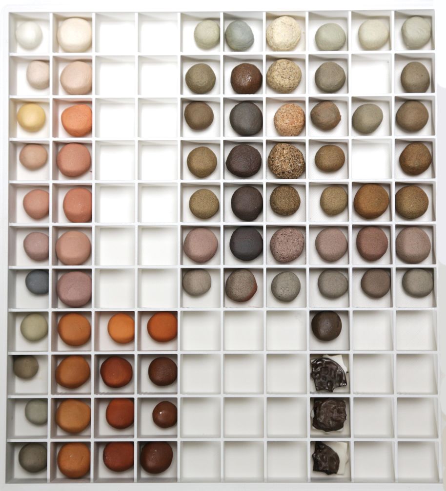 Many different samples of fired wild clay arranged in a white container with small walls