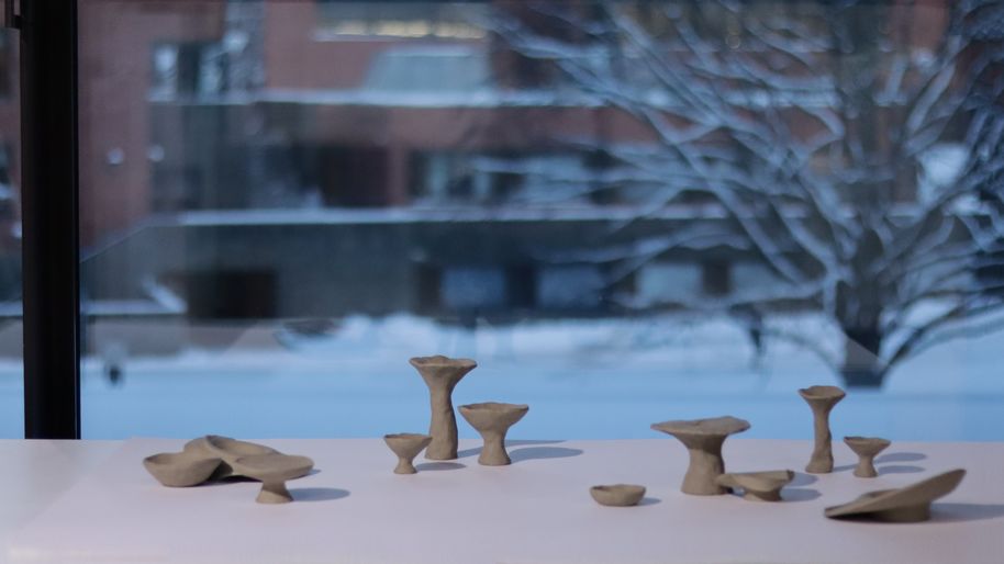 A collection of unfired clay objects, Aalto campus full of snow seen through the window in the background
