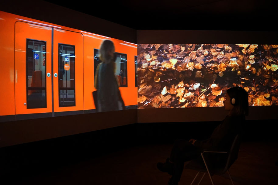 Three screen forming a long immersive video experience, the metro on one screen and autumn leaves on the other