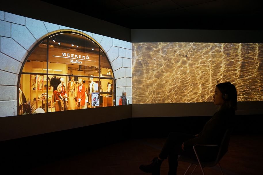 Three screen forming a long immersive video experience, a clothes store on the left and the sea on the right